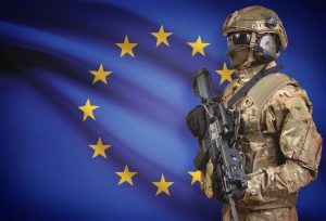 Soldier in helmet holding machine gun with national flag on background - European Union
